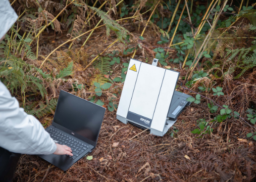 person on ground typing on laptop next to explorer 710 satellite internet terminal